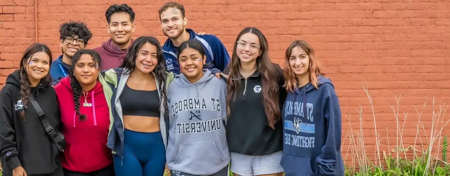 A group of students from latino unidos posing in front of the Greater Quad Cities Hispanic Chamber of Commerce.